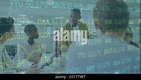 Image of trading board and graph over diverse coworkers discussing report on laptop in office Stock Photo