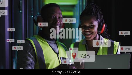 Image of notification bars over african american standing with laptop in server room Stock Photo