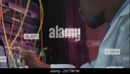 Image of notification bars, african american engineer checking data server system using laptop Stock Photo