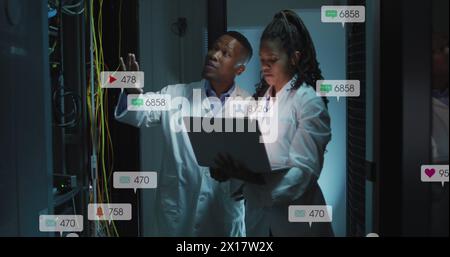 Image of notification bars over diverse engineers discussing on laptop in server room Stock Photo
