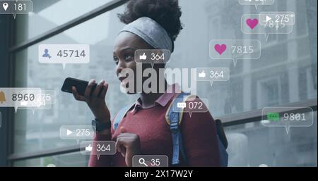 Image of notification bars over african american woman talking on speaker of cellphone Stock Photo