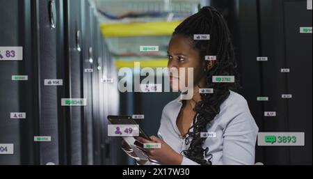 Image of notification bars, female african american engineer using digital tablet in server room Stock Photo