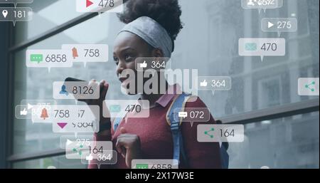 Image of notification bars over african american woman talking on speaker of cellphone Stock Photo