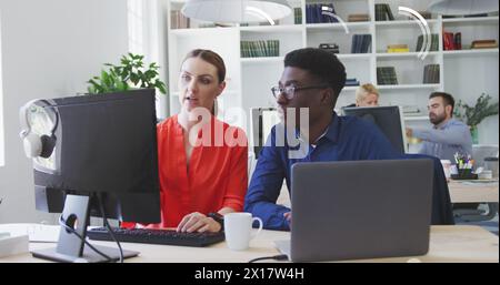 Image of stock market data processing against diverse man and woman discussing at office Stock Photo