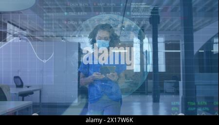 Image of globe and data processing over businesswoman in face mask in office using tablet Stock Photo