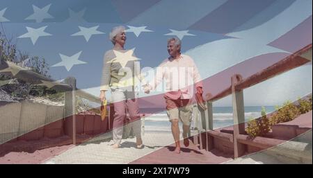 Image of senior caucasian couple holding hands on beach over flag of united states of america Stock Photo