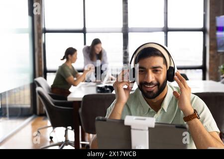 A diverse team working together in a modern business office, Asian male using tablet Stock Photo