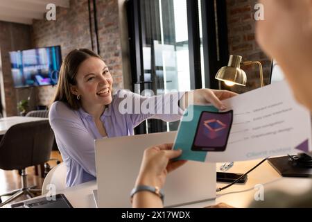 Asian mature professional showing tablet to a young Caucasian colleague in a modern business office Stock Photo