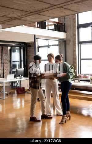 A diverse group of professionals discussing document in a modern business office Stock Photo