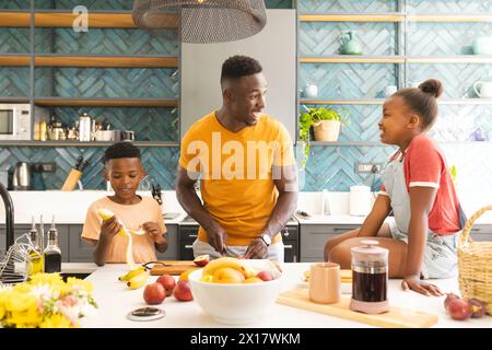 African American father and son preparing breakfast, talking in kitchen at home Stock Photo