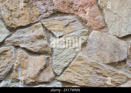 Beautiful beige structural stone wall of the ancient building consists of small bricks. Stock Photo
