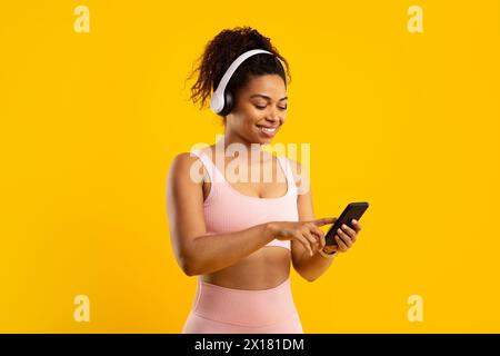 Fit african american lady with headphones using smartphone Stock Photo