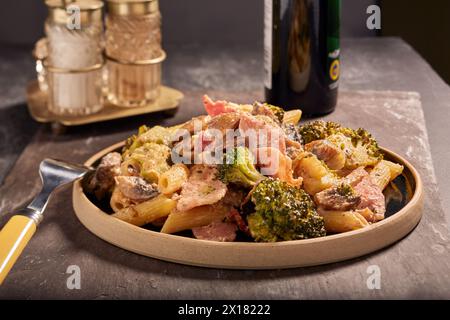 Bacon pasta and vegetables in a nice creamy sauce,with some condiments in the background. Stock Photo