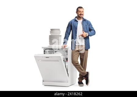 Guy pointing at a dishwasher and a pile of clean white plates isolated on white background Stock Photo