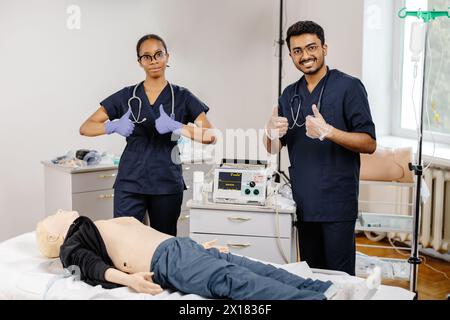 Two doctors in hospital attire standing over a medical dummy, examining and discussing medical procedures and techniques. Stock Photo