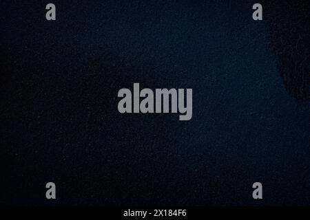 Macro close-up of a dark wall spray painted with black and dark blue. Abstract full frame textured grunge graffiti background with copy space. Stock Photo