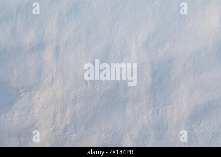Close-up of a clean & uneven wall painted in white. Beautiful sidelight creates soft shadows. Light blue hue. Abstract textured background, copy space Stock Photo