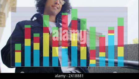 Image of colourful graph over smiling biracial man using smartphone in street Stock Photo