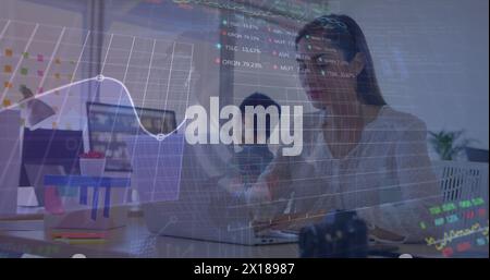 Image of globe, graph, numbers and trading board over caucasian woman working on laptop Stock Photo