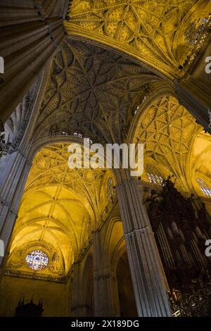 Architectural details on ceiling and stained glass rose window in Interior of The Cathedral of Saint Mary of the See or Seville Cathedral, Seville Stock Photo