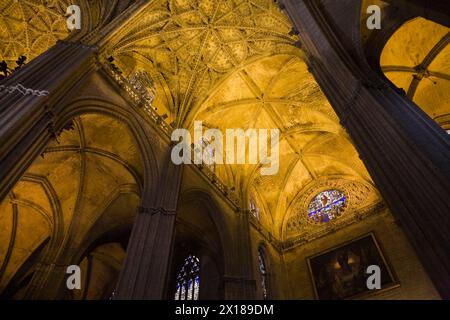 Architectural details on ceiling and stained glass rose window in Interior of The Cathedral of Saint Mary of the See or Seville Cathedral, Seville Stock Photo