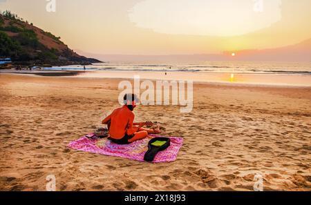 02-19-2019  Goa, IN . Awe view  Goa beach (maybe Karnataka or kerala) . Musician  with guitar on sand beach of Europeam ethnicity and fantastic orange Stock Photo