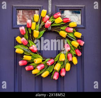 Arrangement of tulips in circular wreath on exterior door marking the start of Easter and springtime Stock Photo