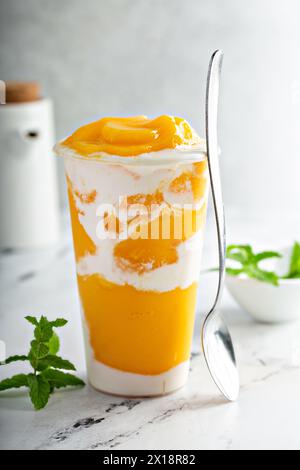 Mango smoothie with whipped coconut cream swirled in a tall cup, refreshing snack or healthy dessert for breakfast Stock Photo