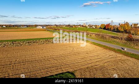 A serene aerial view captures the golden hour over diverse crop fields, with long shadows accentuating the rich textures of the farmland. Stock Photo