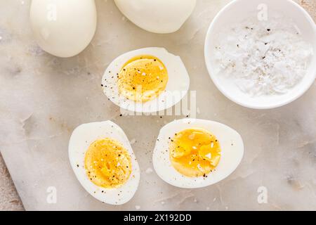 Hard boiled eggs peeled and cut in half with salt and pepper Stock Photo