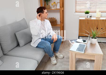 Young man with hearing aid video chatting at home Stock Photo