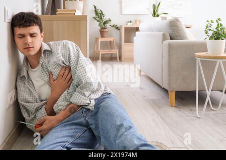 Electrocuted young man with screwdriver sitting near socket at home Stock Photo