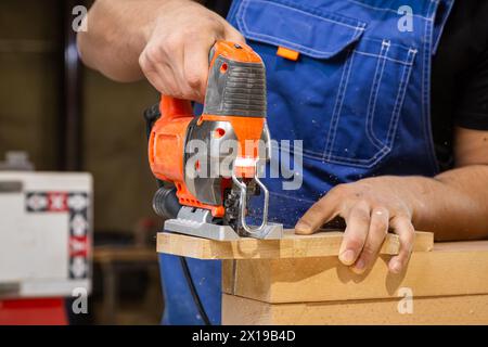 A carpenter using a jigsaw to cut wood cuts bars. Stock Photo