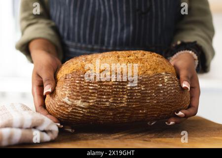 African American young woman holding freshly baked bread at home with copy space Stock Photo