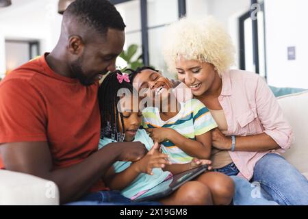 A diverse family enjoying time together at home, looking at a tablet Stock Photo