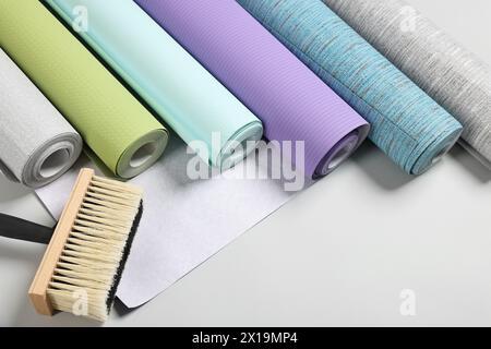 Different wallpaper rolls and brush on light background, above view Stock Photo