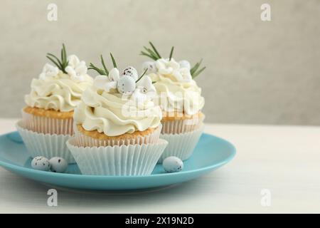 Tasty Easter cupcakes with vanilla cream on light wooden table, space for text Stock Photo