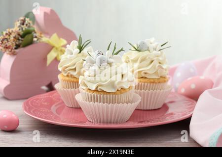 Tasty Easter cupcakes with vanilla cream on wooden table Stock Photo