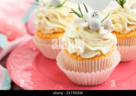 Tasty Easter cupcakes with vanilla cream on table, closeup Stock Photo