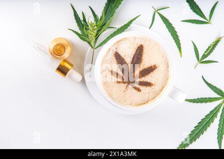 Medical cannabis hemp coffee latte. Cup of creamy whipped coffee with cannabis oil drops and leaf drawn top , with hemp leaves on white background Stock Photo