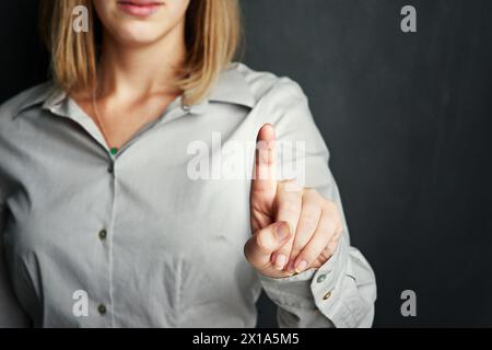 Woman, finger and interface in studio for software, digital data and augmented reality on dark background. Young person or user and touch for Stock Photo