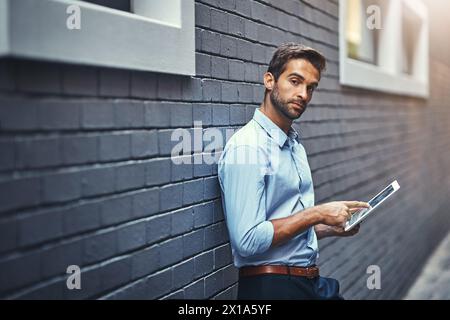 Business man, tablet and portrait in city on web research, email or info online on a wall. Serious, digital tech and person scroll on app or Stock Photo