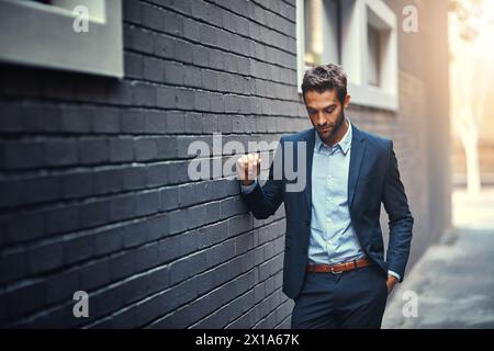 Confident, businessman and thinking in city by wall for corporate fashion, trendy and stylish suit. Male entrepreneur, professional and thoughts in Stock Photo