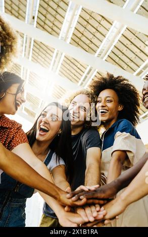 Multiracial happy friends with hands in stack Stock Photo