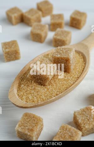 Brown sugar cubes in spoon on white wooden table, closeup Stock Photo