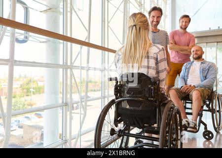 A diverse group of individuals, including persons using wheelchairs, share a moment of joy in a bright, modern space. Stock Photo