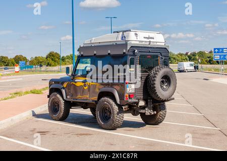 Land Rover Defender with roof rack in parking lot on a clear day. Stock Photo