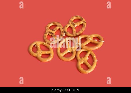 Several dry and salty pretzels lie on a red background. Stock Photo