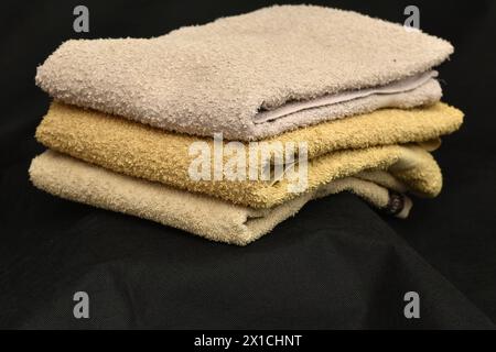 On a dark background, terry towels for the body are removed, which lie in a pile. Stock Photo
