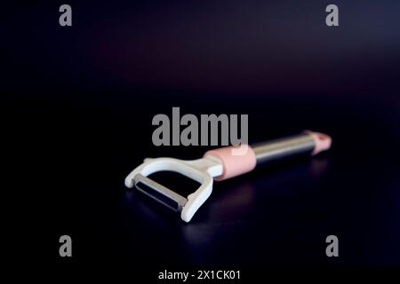 a pink vegetable peeler on a black background Stock Photo